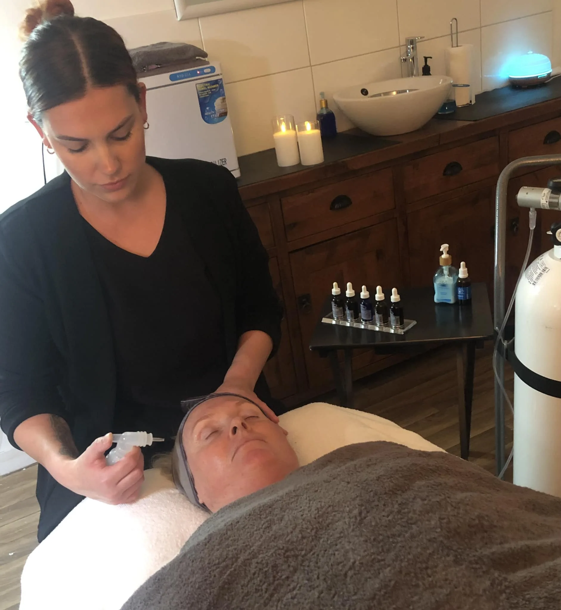 Therapist performing a serum facial treatment on a reclining client in the Forever Young Werribee treatment room