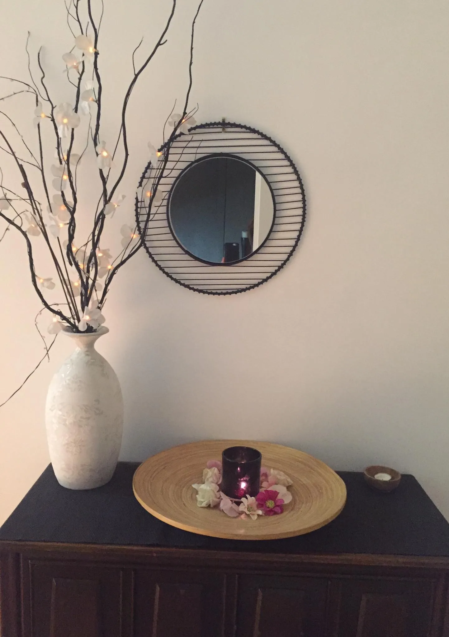 Styled decor vignette — white vase with blossom branches, round mirror and candle arrangement